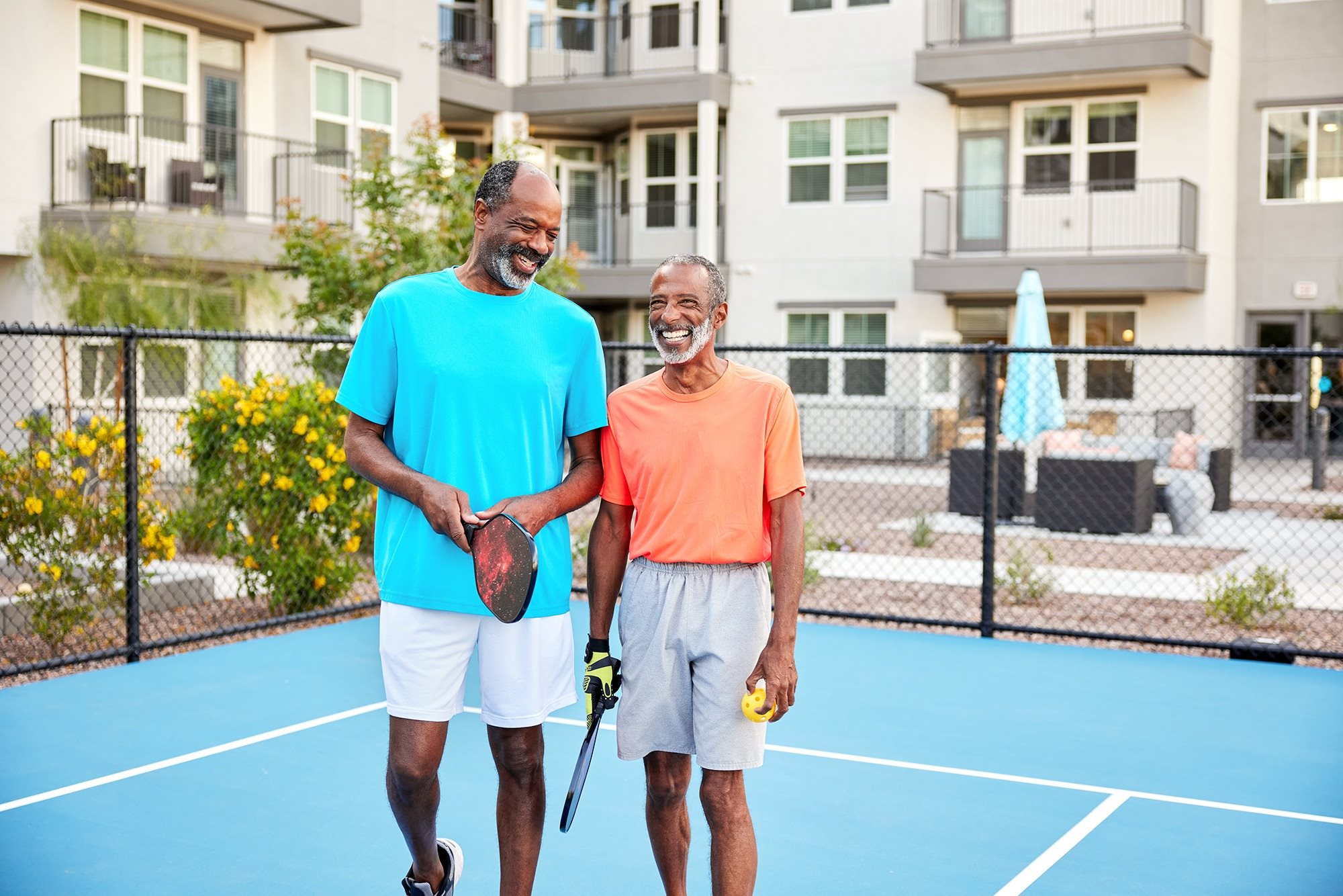 Two men standing on a tennis court holding tennis rackets.
